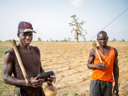 Farmers in the Sahelian village of Diouna in southern Mali listen to the radio as they prepare their field for planting. Photo: F. Fiondella (IRI)